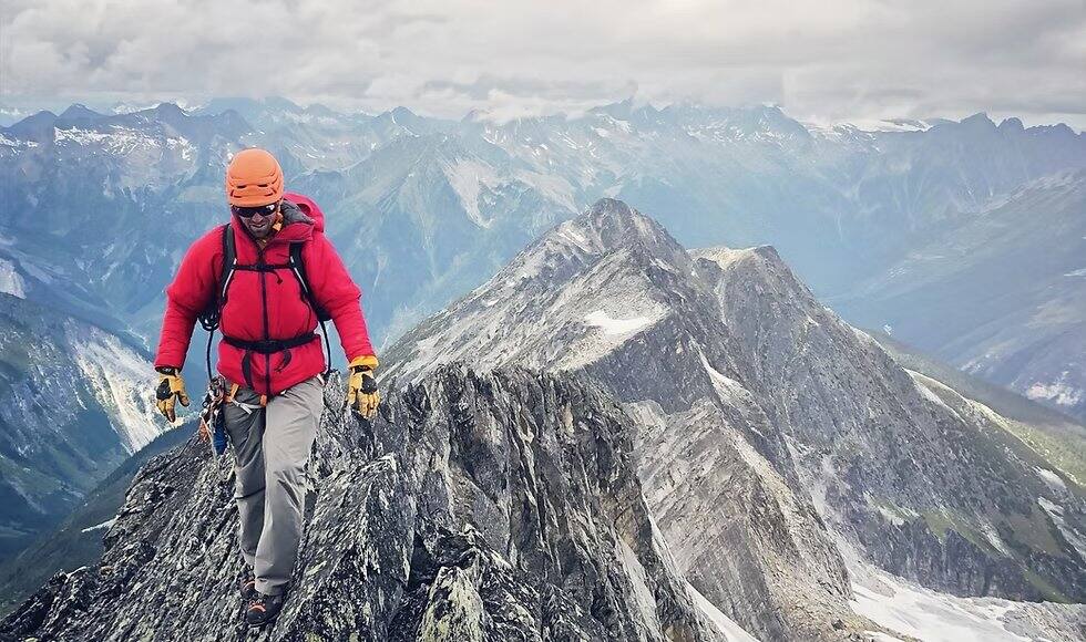 A climber on an exposed rock ridge in the Selkirk Mountains near Rogers Pass in summer